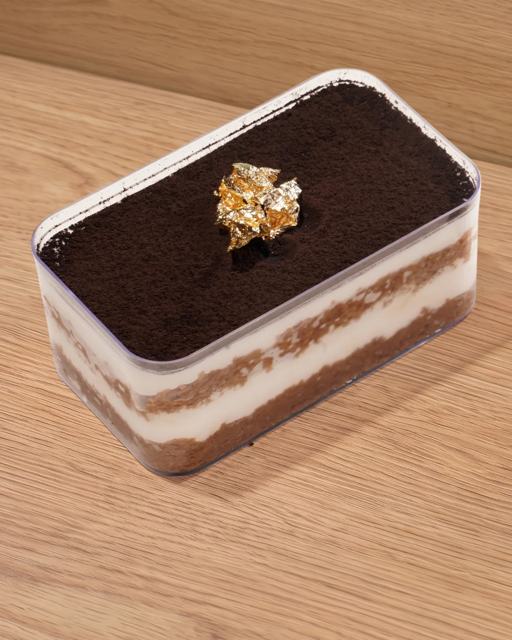 FOJO classic tiramisu in a clear box, topped with cocoa and gold leaf