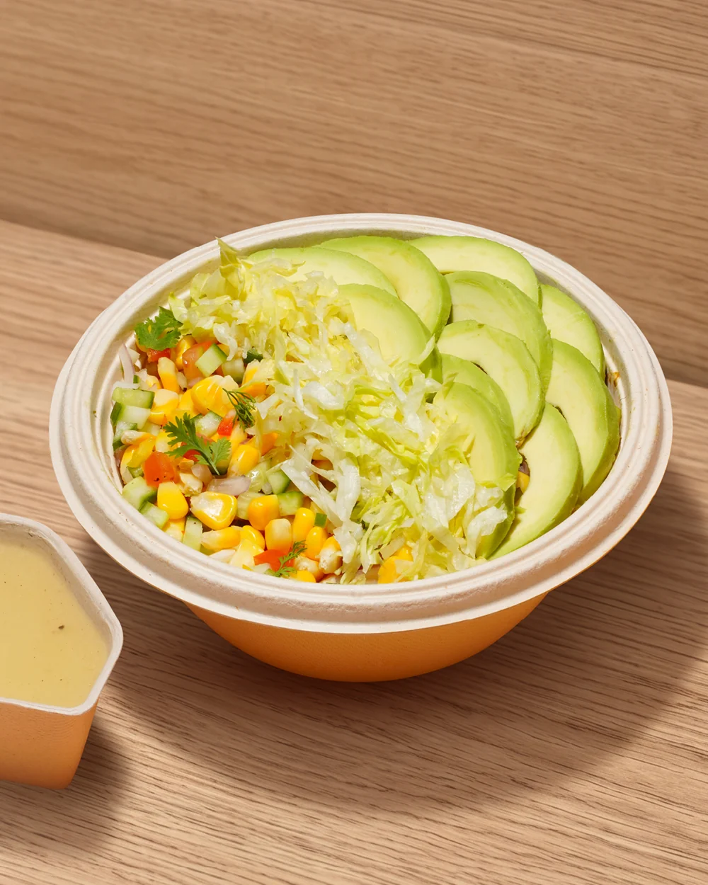 A FOJO salad bowl with lettuce, corn and cucumber, served with dressing on the side